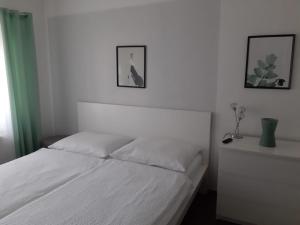 a white bed in a bedroom with two pictures on the wall at Ferienwohnung Leithaberg in Eisenstadt