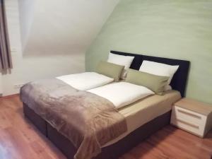 een bed met witte kussens en een bruine deken bij Greenhouse in Baiersbronn