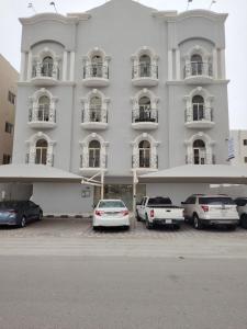 un grand bâtiment blanc avec des voitures garées dans un parking dans l'établissement شقق لين, à Khobar