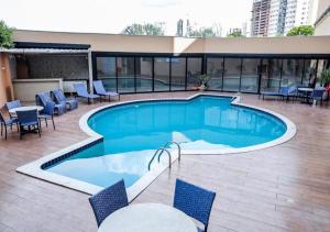 ein großes Schwimmbecken mit Stühlen und einem Tisch in der Unterkunft Hotel Inter Cuiaba in Cuiabá