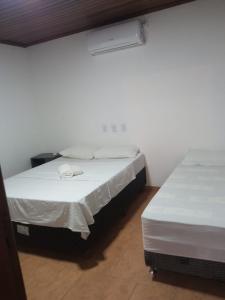 2 camas en una habitación con paredes blancas en hotel fazenda ctk, en Santa Cruz do Sul