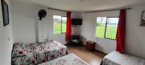 1 dormitorio con 2 camas y ventanas con cortinas rojas en Finca hotel los cocos, en Montenegro