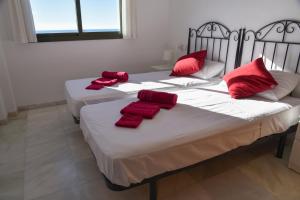 drie bedden in een kamer met rode kussens erop bij Ático en Mar de Nerja in Nerja