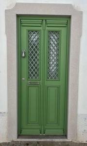 a green door in a building with a window at Casa Porta Velha 2 Bed in Tavira