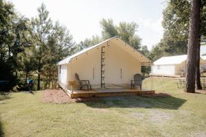a large white tent with two chairs in a yard at Glamping Tents 2 Queens at Lake Guntersville State Park in Guntersville