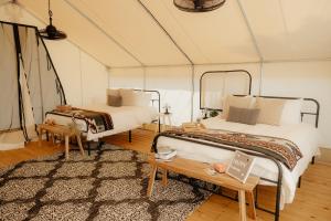 two beds in a tent with a rug at Glamping Tents 2 Queens at Lake Guntersville State Park in Guntersville