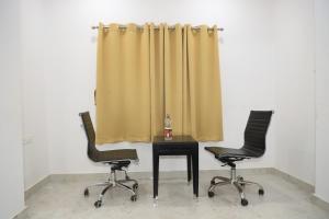 duas cadeiras e uma mesa com uma cortina amarela em Hotel Moon Residency Near Yashobhoomi Convention Centre em Nova Deli