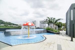 a fountain with a red umbrella in a pool at Japandi Family Play Suite with Slide Bunk Bed in Kajang