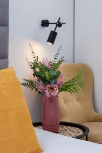 a vase of flowers on a table with a lamp at Cracow Miodowa 42 Elegant Studios by Renters in Krakow