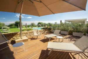 a patio with chairs and an umbrella and a pool at Masseria Della Volpe in Casale Modica