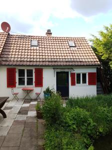 a white house with red shutters and a patio at Kl. Cottage im Grünen, n. S-Bahn in Stuttgart