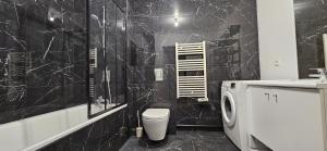 een zwart marmeren badkamer met een toilet en een wastafel bij Cosy'part Gold. in Bezons