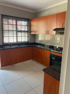 a kitchen with wooden cabinets and a counter top at M D J Hayfields Guest House in Pietermaritzburg