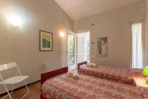 a bedroom with two beds and a chair and a window at Villa Margherita Sardegna 250m from the beach in Fort Village