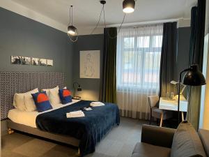 a bedroom with a bed with blue sheets and a desk at Zeit Hotel in Līgatne