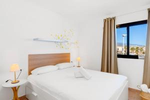Un dormitorio blanco con una cama grande y una ventana en MEDANO4YOU Marina Home By The Sea en El Médano