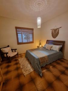 een slaapkamer met een bed, een stoel en een raam bij Daldeia in São Pedro da Aldeia