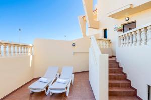 un balcón con sillas blancas y escaleras en una casa en MEDANO4YOU Marina Home By The Sea, en El Médano