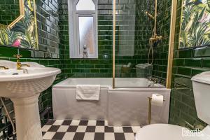 La salle de bains est pourvue de carrelage vert, d'une baignoire et d'un lavabo. dans l'établissement The Church House - 3 Bedroom House + Free Parking, à Nottingham