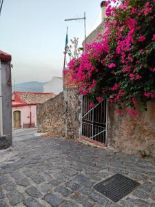un edificio in pietra con fiori rosa di Borgo Di Taormina Apartments a Gaggi