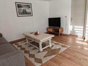 ein Wohnzimmer mit einem Couchtisch und einem TV in der Unterkunft Appartement au sein d'une maison in Issenheim