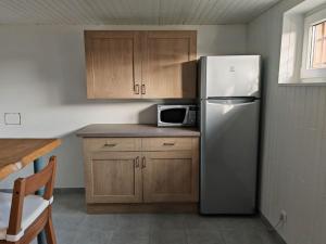 La cuisine est équipée d'un réfrigérateur en acier inoxydable et de placards en bois. dans l'établissement Appartement au sein d'une maison, à Issenheim