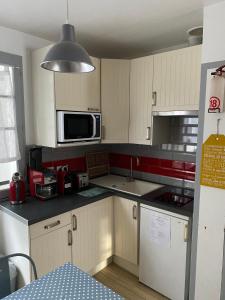 a kitchen with white cabinets and a microwave at Studio Noirmoutier Plage in La Guérinière
