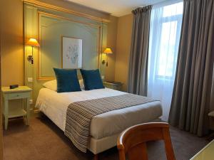 a bedroom with a bed with blue pillows and a window at Hôtel EUROPE in Saverne