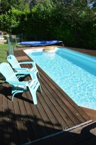two chairs sitting on a deck next to a swimming pool at Chalet, calme, absolu, superbe vue, et piscine (en été) in Ventenac-Cabardès