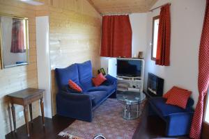 a living room with blue couches and a tv at Chalet, calme, absolu, superbe vue, et piscine (en été) in Ventenac-Cabardès