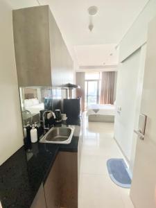 a kitchen with a sink and a living room at Cozy Studio Unit @Ciputra World Surabaya in Surabaya