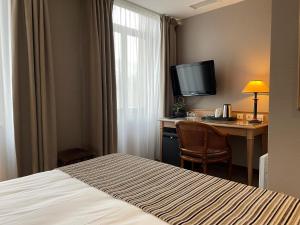 a hotel room with a bed and a desk with a television at Hôtel EUROPE in Saverne +23 photos
