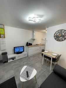 ein Wohnzimmer mit einem Tisch und einem TV in der Unterkunft La maisonnette Saint-quentinoise in Saint-Quentin