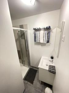 a white bathroom with a shower and a sink at La maisonnette Saint-quentinoise in Saint-Quentin