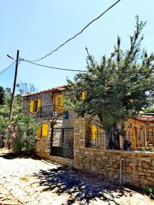 una casa de piedra con puertas amarillas y una valla en Ilios Guest House, en Gokceada Town