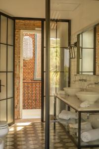un bagno con due lavandini, servizi igienici e una porta di Casa Del Val- Villa Maria a San Bernardino