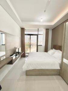 een slaapkamer met een wit bed en een groot raam bij Cozy Studio Unit @Ciputra World Surabaya in Surabaya