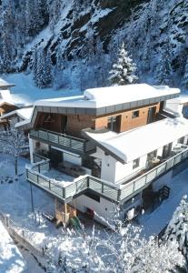 ein Haus im Schnee in den Bergen in der Unterkunft Apart Aurelia in Längenfeld