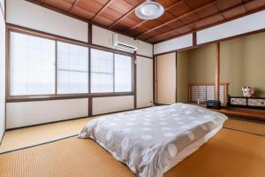 a bedroom with a large bed and two windows at KIX House Wakeikan 和憩館 in Izumi-Sano