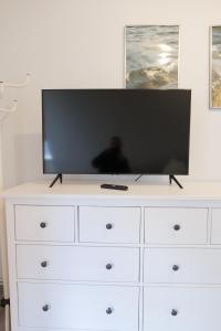 a flat screen tv on top of a white dresser at Bändsel Herberge Kaffetiet - ABC363 in Wismar