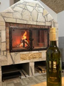 a bottle of wine next to a brick fireplace at Apartman BARIŠIĆ 2 in Kupres