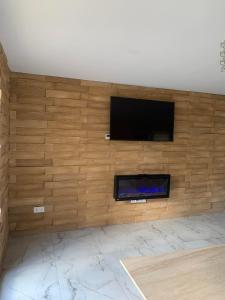 a living room with a wooden wall with a flat screen tv at Dom w górach z bilardem in Juszczyna