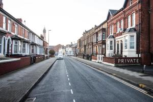 eine leere Straße mit einem Auto, das die Straße hinunterfährt in der Unterkunft Blackpool Townhouse in Blackpool