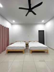 two beds in a room with a ceiling fan at HeyFam Homestay in Sekinchan