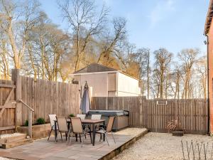 eine Terrasse mit einem Tisch, Stühlen und einem Zaun in der Unterkunft Nellies Shed, Wolds Way Holiday Cottages, 3 bed spacious cottage in Cottingham