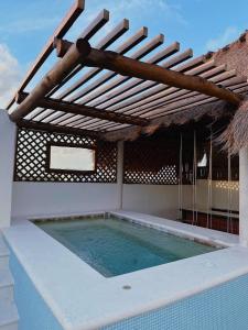 uma piscina exterior com telhado de palha e uma piscina em La Casita de Jonas em Puerto Morelos