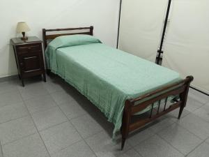 B&B Luján de Cuyo في سيوداد لوجان دي كويو: غرفة نوم مع سرير وطاولة مع بطانية خضراء