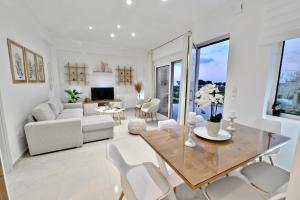 una sala de estar blanca con mesa y sillas en Magedico 150m from the beach en Kissamos