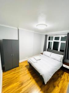 a bedroom with a large white bed and a window at Ravensbury Home in Mitcham