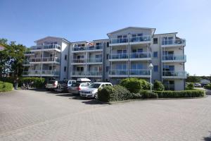 a large apartment building with cars parked in a parking lot at Yachthafenresidenz-Wohnung-8304-860 in Kühlungsborn